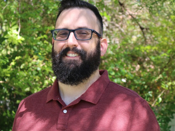Photo of man with beard and glasses smiling at camera