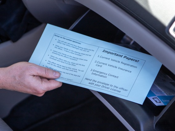 Hand pulling blue envelope from glove compartment of car