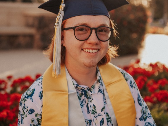 Headshot of Austin smiling at the camera wearing graduation cap