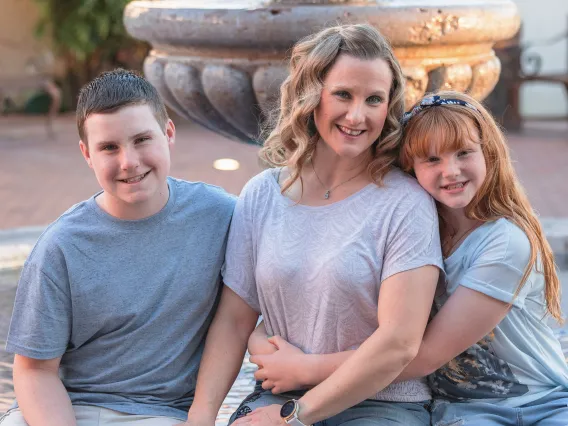 An image of a woman sitting by a fountain with children