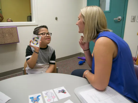 A young boy holding up a card and looking at a woman