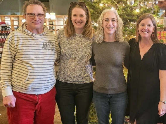 Four adults standing together and smiling at the camera.