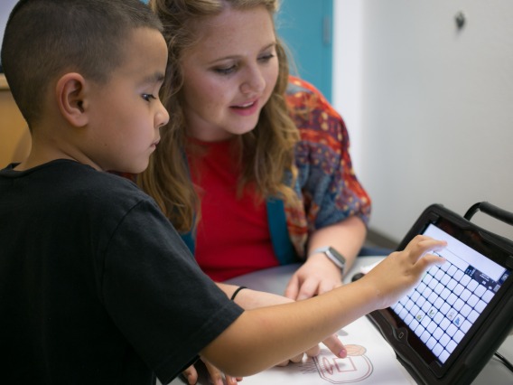 A young client uses his alternative and augmentative communication device
