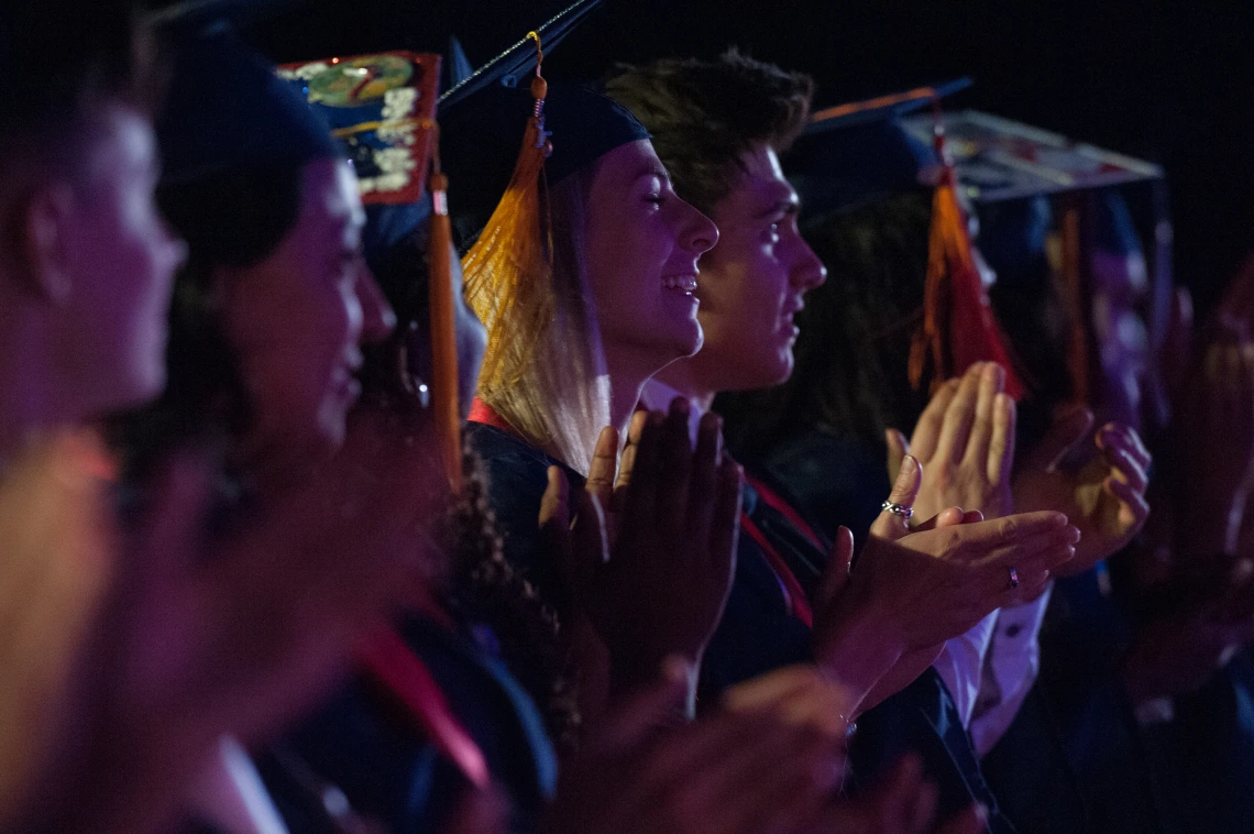 Graduates in cap and gown clapping