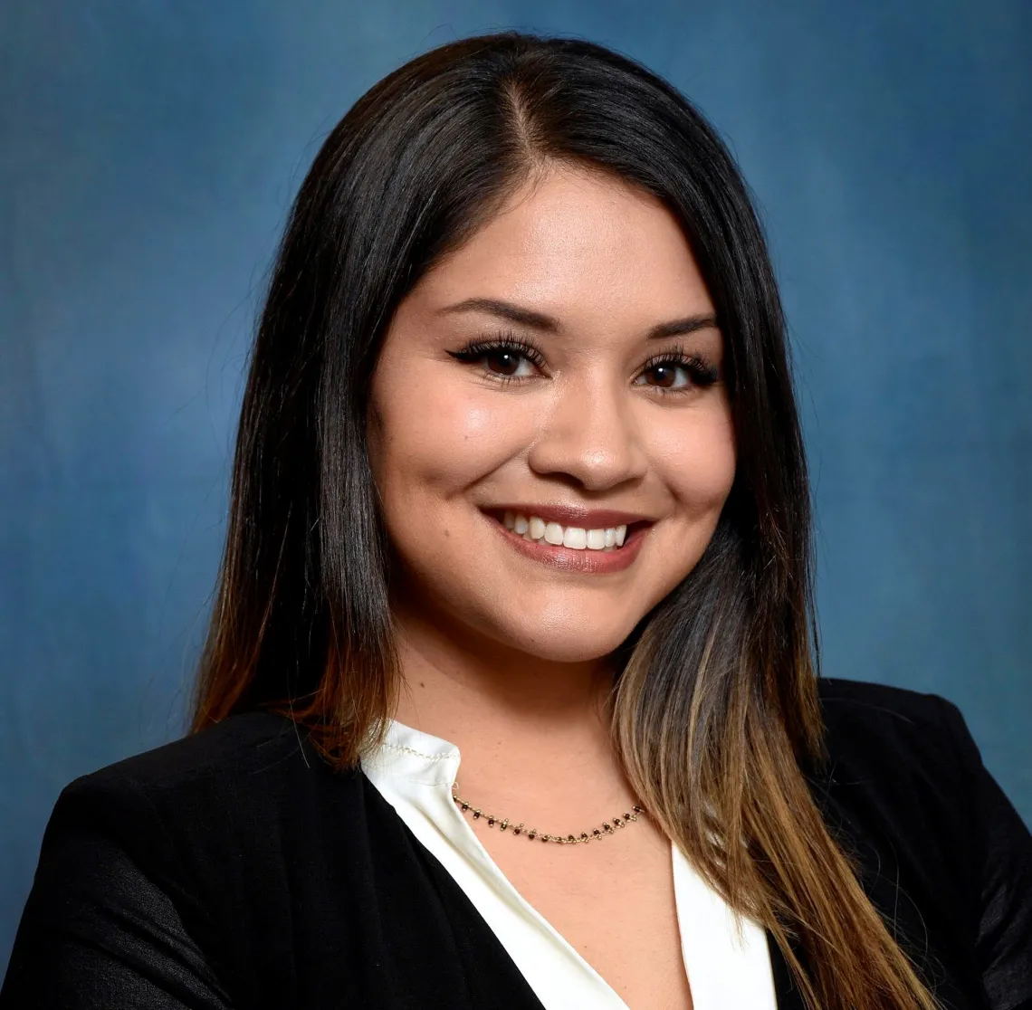 Photo of woman in black blazer smiling at camera