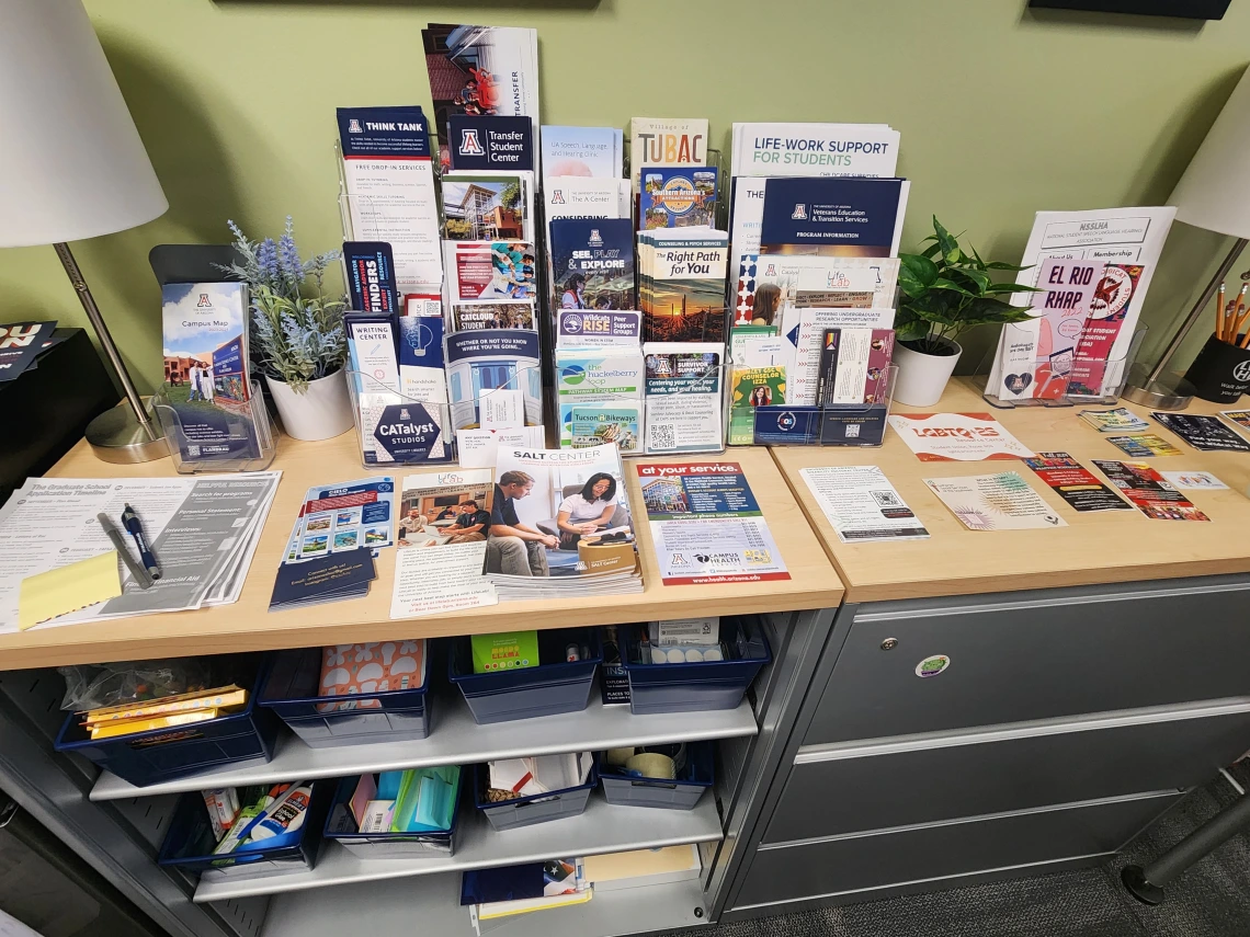 desk covered in flyers and pamphlets for UA-related or Tucson-related resources