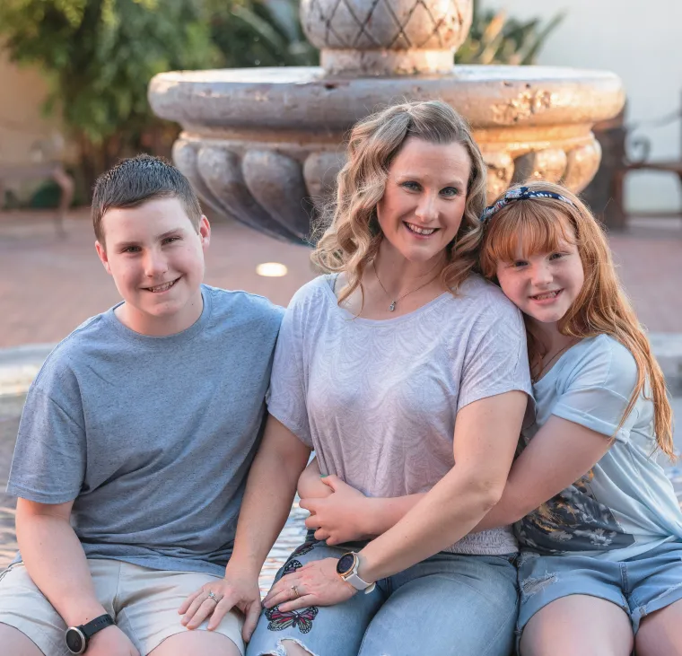 An image of a woman sitting by a fountain with children