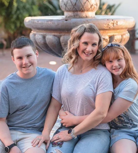 An image of a woman sitting by a fountain with children