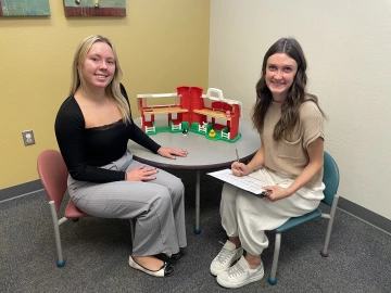 L4 Lab members Brooke and Lauren sitting by a circle table