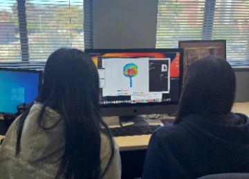 Dr. Kielar lab photo; two lab students looking at a brain scan on the computer