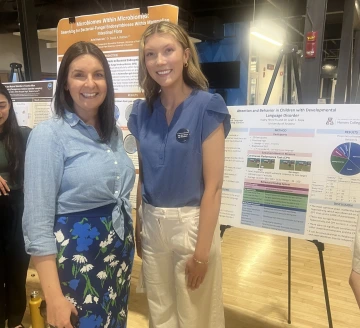 Undergraduate researcher with faculty advisor in front of research poster