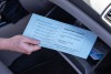 Hand pulling blue envelope from glove compartment of car